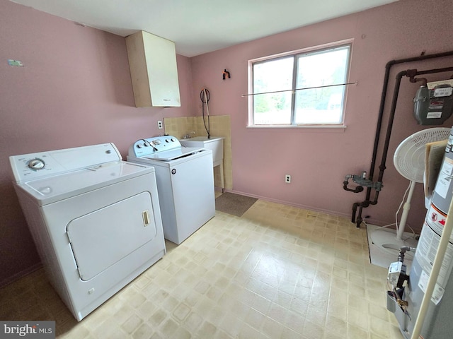 clothes washing area with separate washer and dryer, light flooring, cabinet space, and baseboards