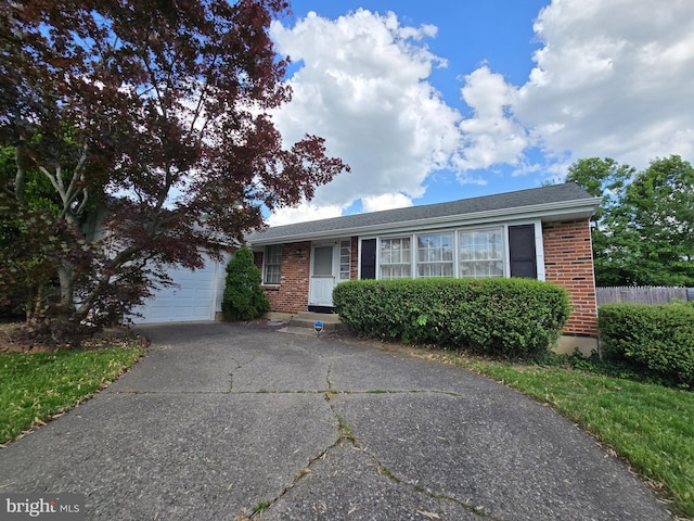 view of front of house featuring brick siding, an attached garage, driveway, and fence