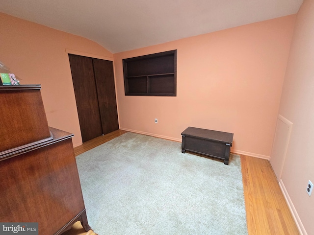 bedroom featuring a closet, wood finished floors, vaulted ceiling, and baseboards
