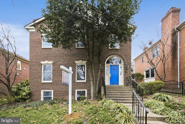 view of front of home with brick siding and fence