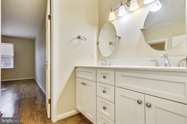 bathroom featuring wood finished floors, double vanity, and baseboards