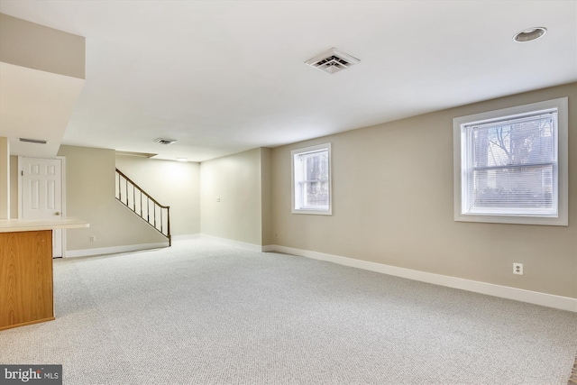 basement featuring stairs, baseboards, and light carpet