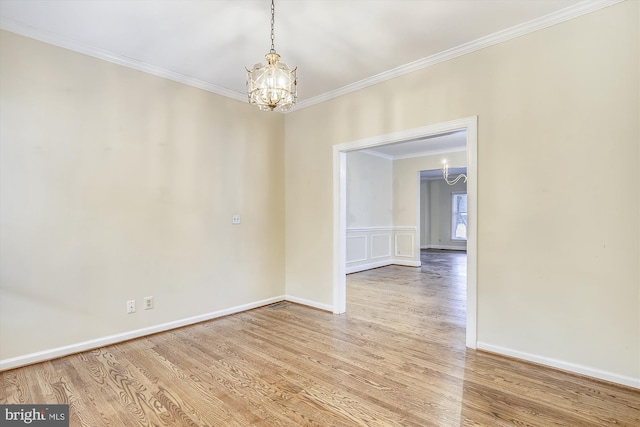 spare room with a chandelier, ornamental molding, wood finished floors, and baseboards