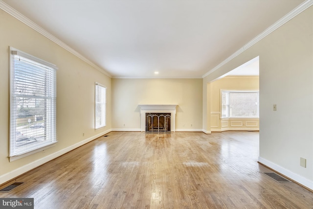 unfurnished living room featuring baseboards, wood finished floors, and crown molding