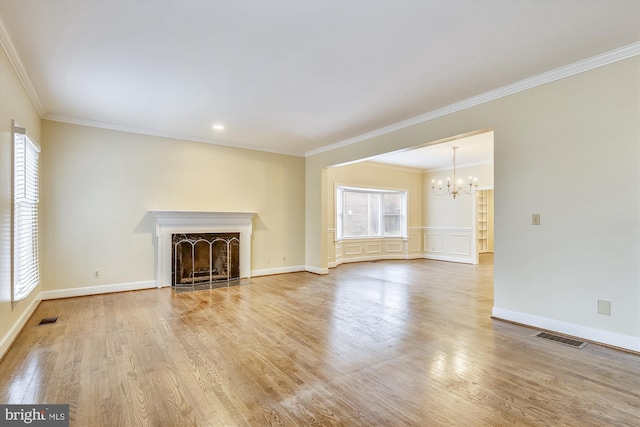 unfurnished living room featuring a chandelier, ornamental molding, wood finished floors, a fireplace with flush hearth, and baseboards