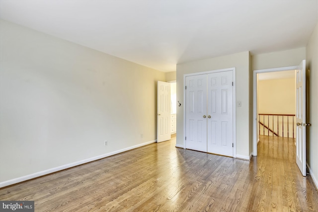unfurnished bedroom with wood finished floors, baseboards, and a closet