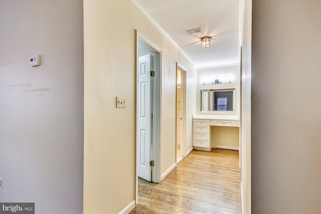 hall with crown molding, light wood-style floors, and baseboards