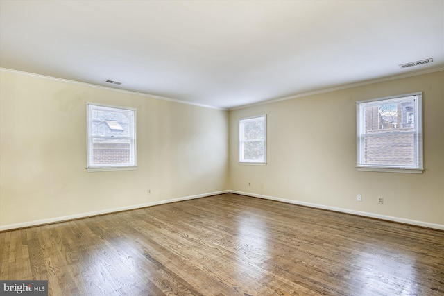 spare room with wood finished floors, ornamental molding, and baseboards