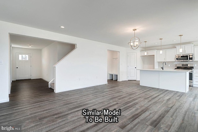 unfurnished living room featuring wood finished floors, recessed lighting, baseboards, a sink, and a chandelier
