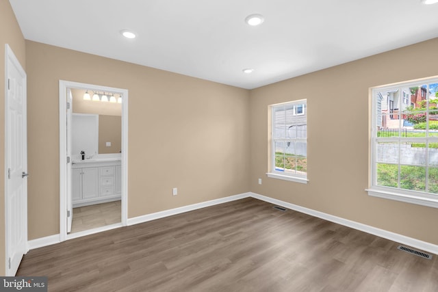 4820 Hayes St NE, Washington, DC 20019 - unfurnished bedroom featuring multiple windows, wood finished floors, baseboards, recessed lighting, and ensuite bath