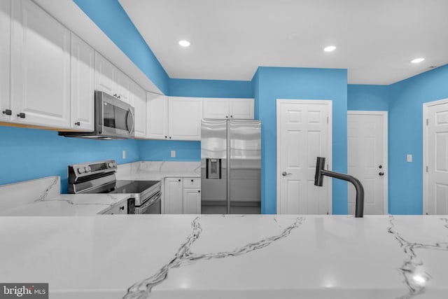 4820 Hayes St NE, Washington, DC 20019 - kitchen featuring stainless steel appliances, white cabinets, recessed lighting, and light stone countertops