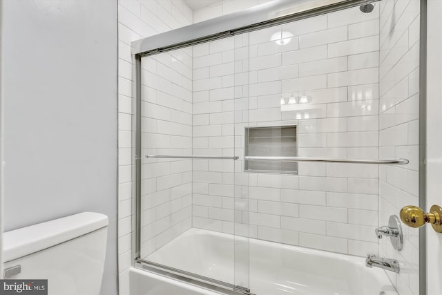 bathroom featuring combined bath / shower with glass door and toilet