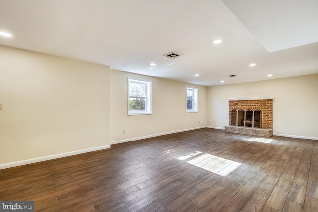 unfurnished living room featuring dark wood finished floors, baseboards, recessed lighting, and a brick fireplace