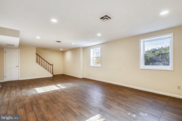 spare room with stairway, baseboards, wood finished floors, and recessed lighting