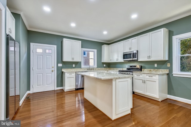 kitchen with stainless steel appliances, white cabinetry, wood finished floors, ornamental molding, and recessed lighting