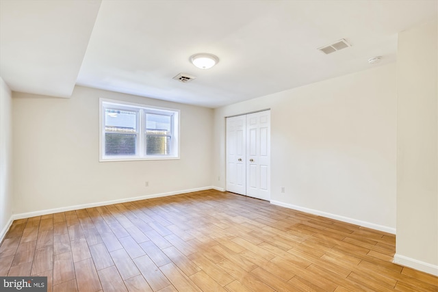 unfurnished bedroom with light wood finished floors, baseboards, and a closet