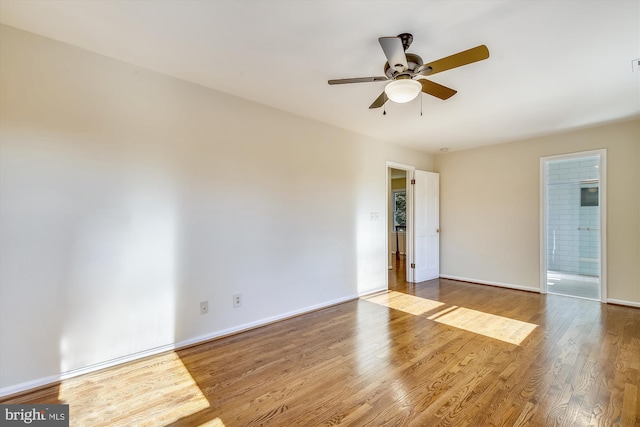 empty room with wood finished floors, a ceiling fan, and baseboards