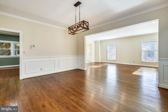 unfurnished dining area featuring crown molding, a chandelier, wood finished floors, and wainscoting