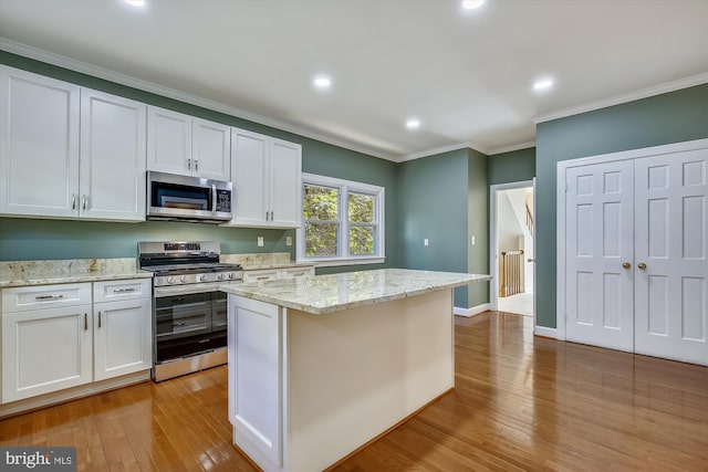 kitchen featuring appliances with stainless steel finishes, light wood-style floors, ornamental molding, white cabinetry, and recessed lighting