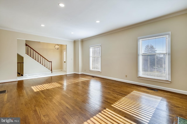 unfurnished living room with crown molding, wood finished floors, baseboards, stairway, and recessed lighting