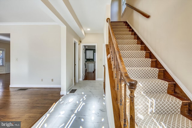 stairs with crown molding, wood finished floors, and baseboards