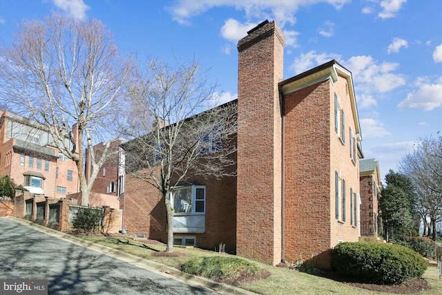 view of property exterior with a chimney and brick siding