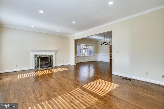 unfurnished living room with ornamental molding, recessed lighting, a high end fireplace, wood finished floors, and baseboards