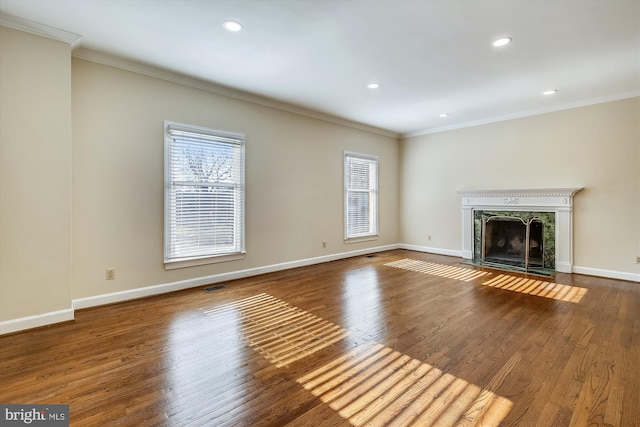unfurnished living room featuring healthy amount of natural light, ornamental molding, a high end fireplace, recessed lighting, and wood finished floors