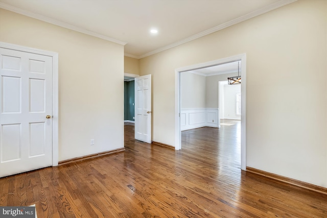 spare room featuring crown molding, wood finished floors, a chandelier, and baseboards