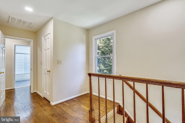 corridor featuring wood finished floors, an upstairs landing, and baseboards