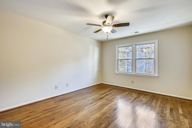 spare room with wood finished floors, baseboards, and a ceiling fan
