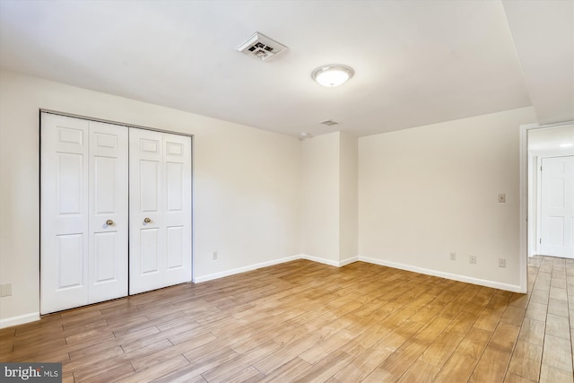 unfurnished bedroom featuring light wood-type flooring, baseboards, and a closet