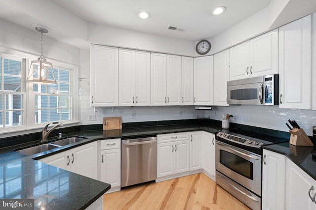 kitchen featuring appliances with stainless steel finishes, a sink, white cabinets, hanging light fixtures, and recessed lighting