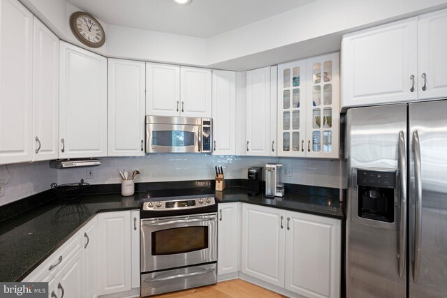 kitchen featuring stainless steel appliances, white cabinets, glass insert cabinets, and backsplash