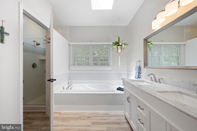 full bath with a skylight, wood finished floors, a shower stall, and a bath