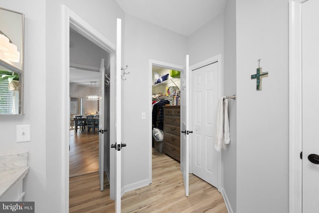 hallway featuring light wood finished floors and baseboards