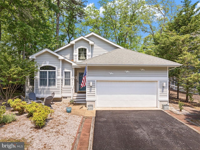 traditional home with driveway, an attached garage, and roof with shingles