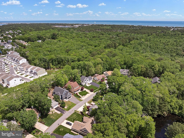 view of property location with a heavily wooded area, nearby suburban area, and a large body of water