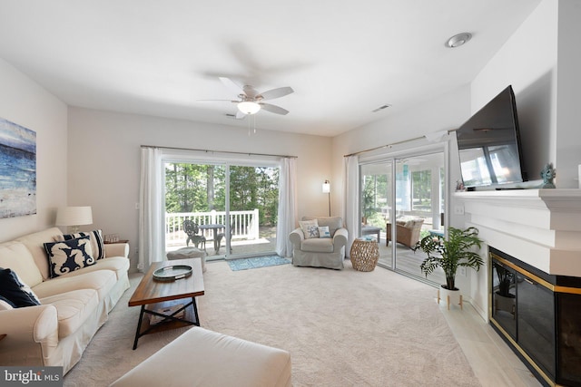 living area featuring a ceiling fan and a fireplace with flush hearth