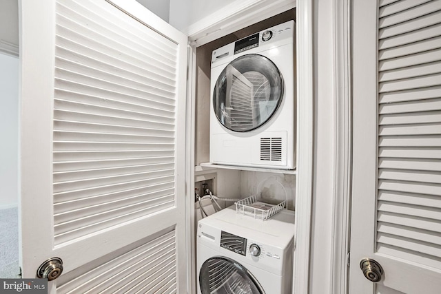 clothes washing area with stacked washing machine and dryer