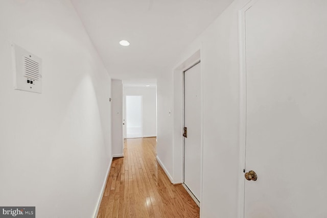 hallway featuring light wood-type flooring, baseboards, and recessed lighting