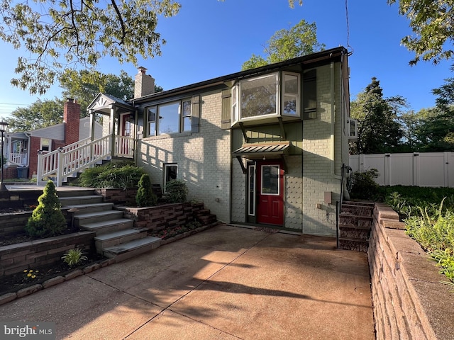 8107 Chester St, Takoma Park, MD 20912 - rear view of property with brick siding, a patio, fence, stairway, and a chimney
