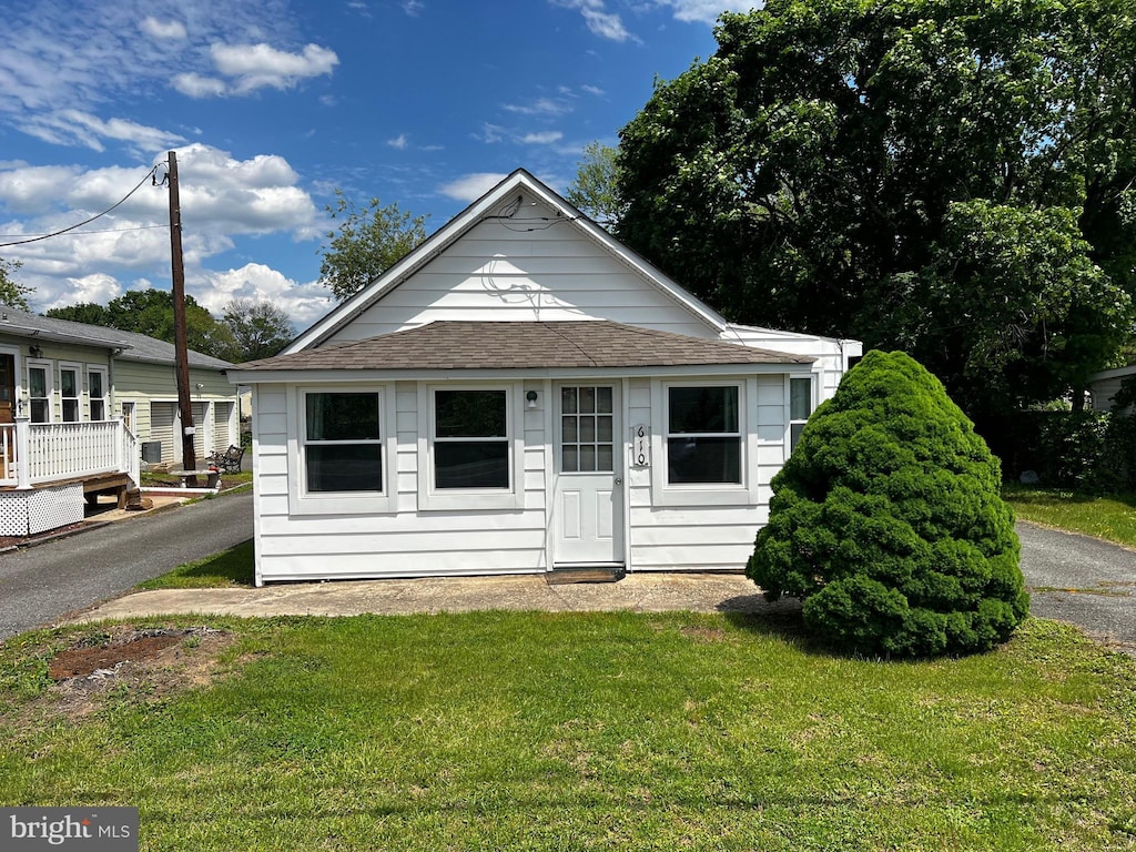 view of front of house with a shingled roof and a front lawn