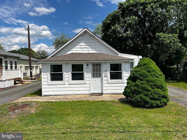 view of front of house with a shingled roof and a front lawn