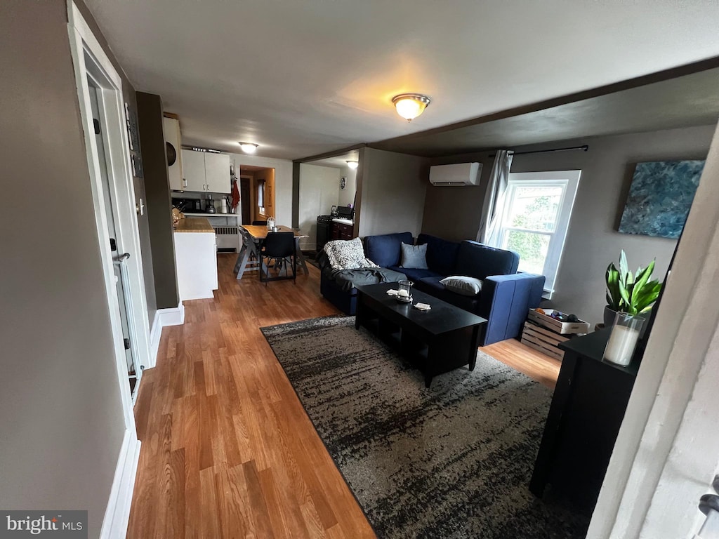 living room featuring wood finished floors and a wall mounted air conditioner