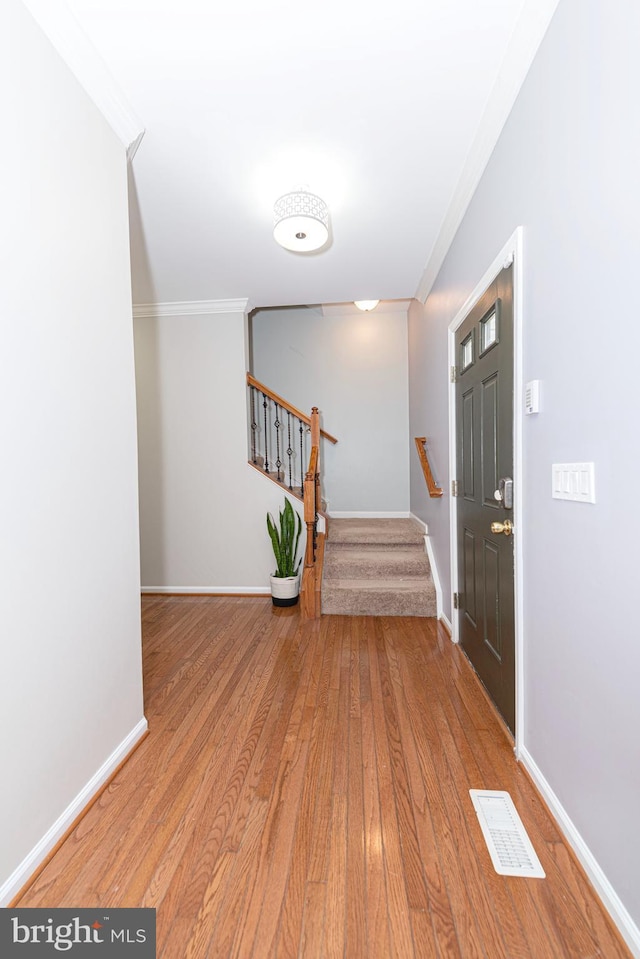 entrance foyer with crown molding, stairs, wood finished floors, and baseboards