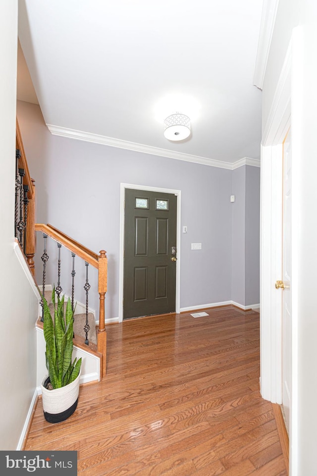 foyer entrance with stairway, ornamental molding, wood finished floors, and baseboards