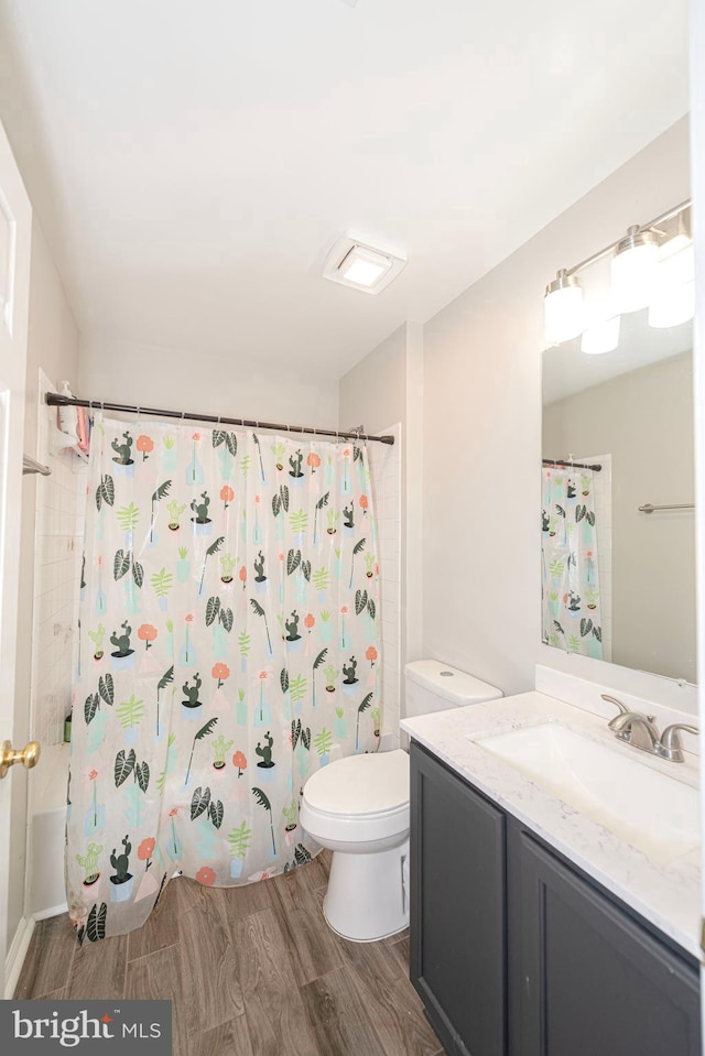 full bathroom with wood finished floors, toilet, vanity, and shower / tub combo