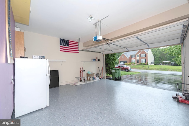 garage featuring freestanding refrigerator and a garage door opener