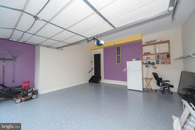 garage featuring freestanding refrigerator and a garage door opener